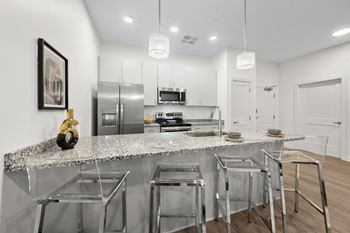 A modern kitchen with a granite countertop and stainless steel appliances.